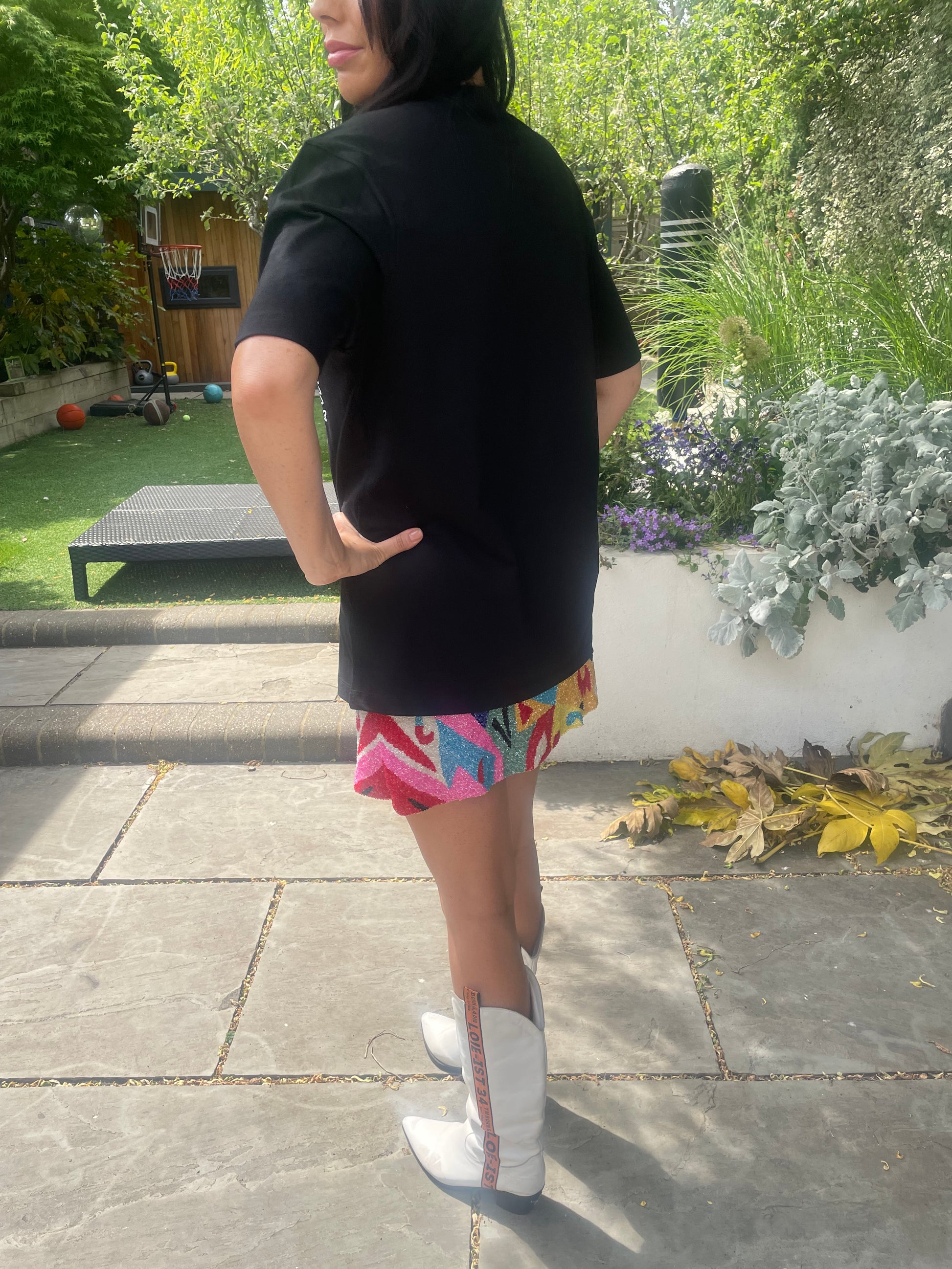 Person wearing a black dress with colorful accents in an outdoor setting