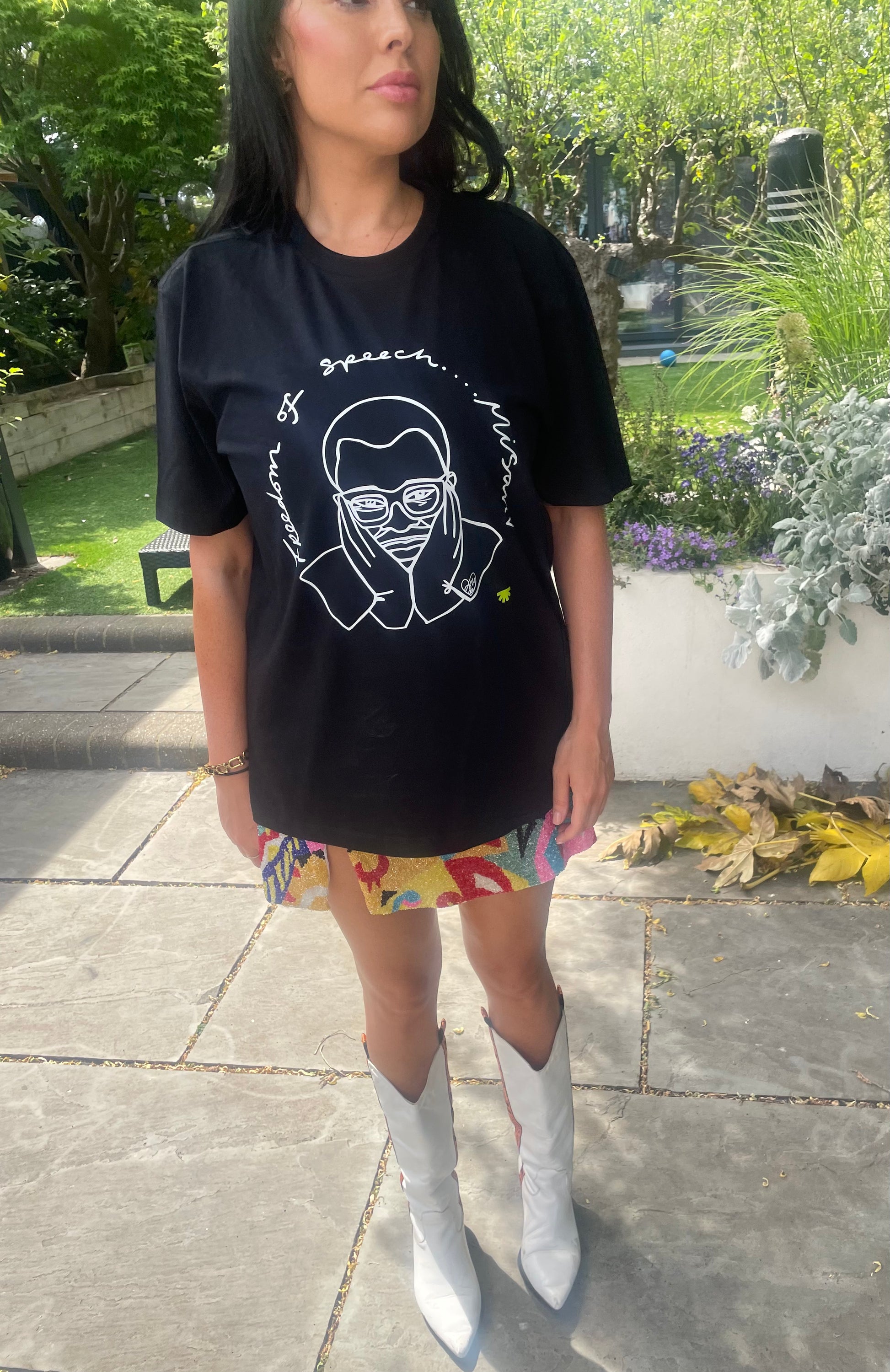 Woman wearing a black t-shirt with a graphic design outdoors.